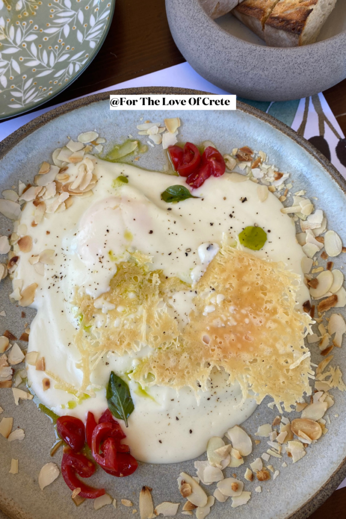 Staka with eggs: Fresh eggs, staka cheese, graviera cheese flakes, toasted almonds, cherry tomatoes, basil, parsley and garlic oil from Biolea Extra Virgin Olive Oil. Served with sourdough bread. At Biolea Astrikas Estate in Chania, Crete.