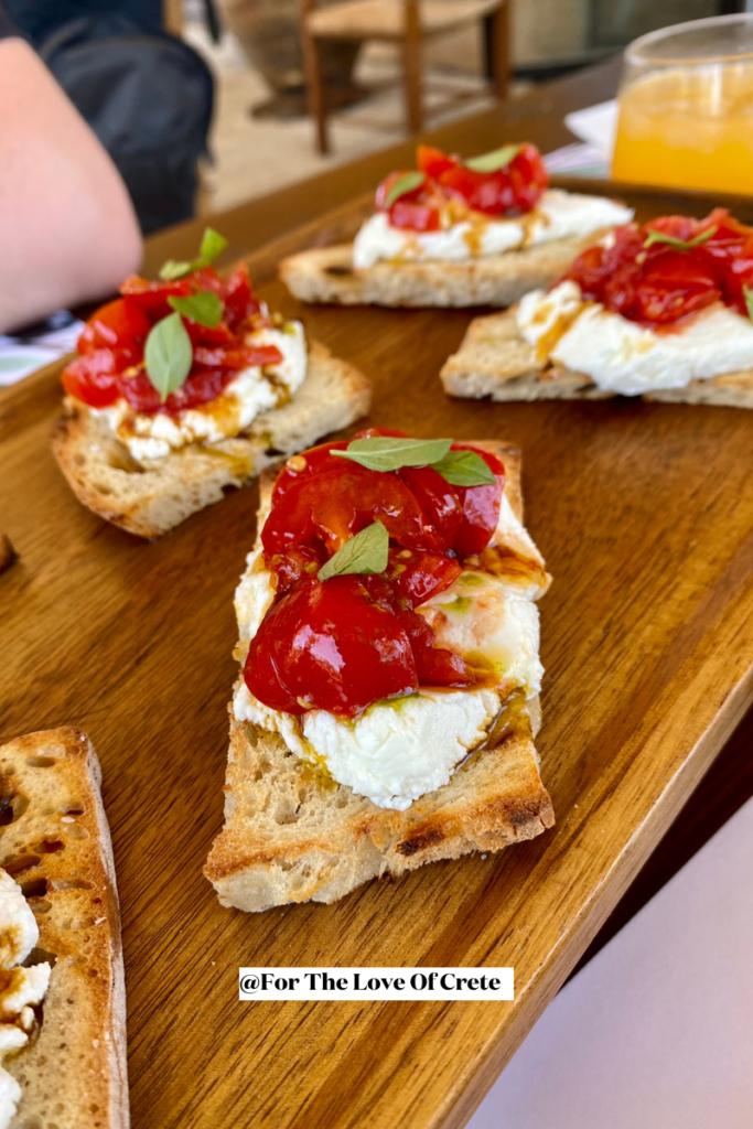 Grilled bruschetta topped with soft myzithra goat cheese, conficherry tomatoes, petimezi syrup, parsley and garlic oil from Biolea Extra Virgin Olive Oil. At Biolea Astrikas Estate, Chania, Crete.