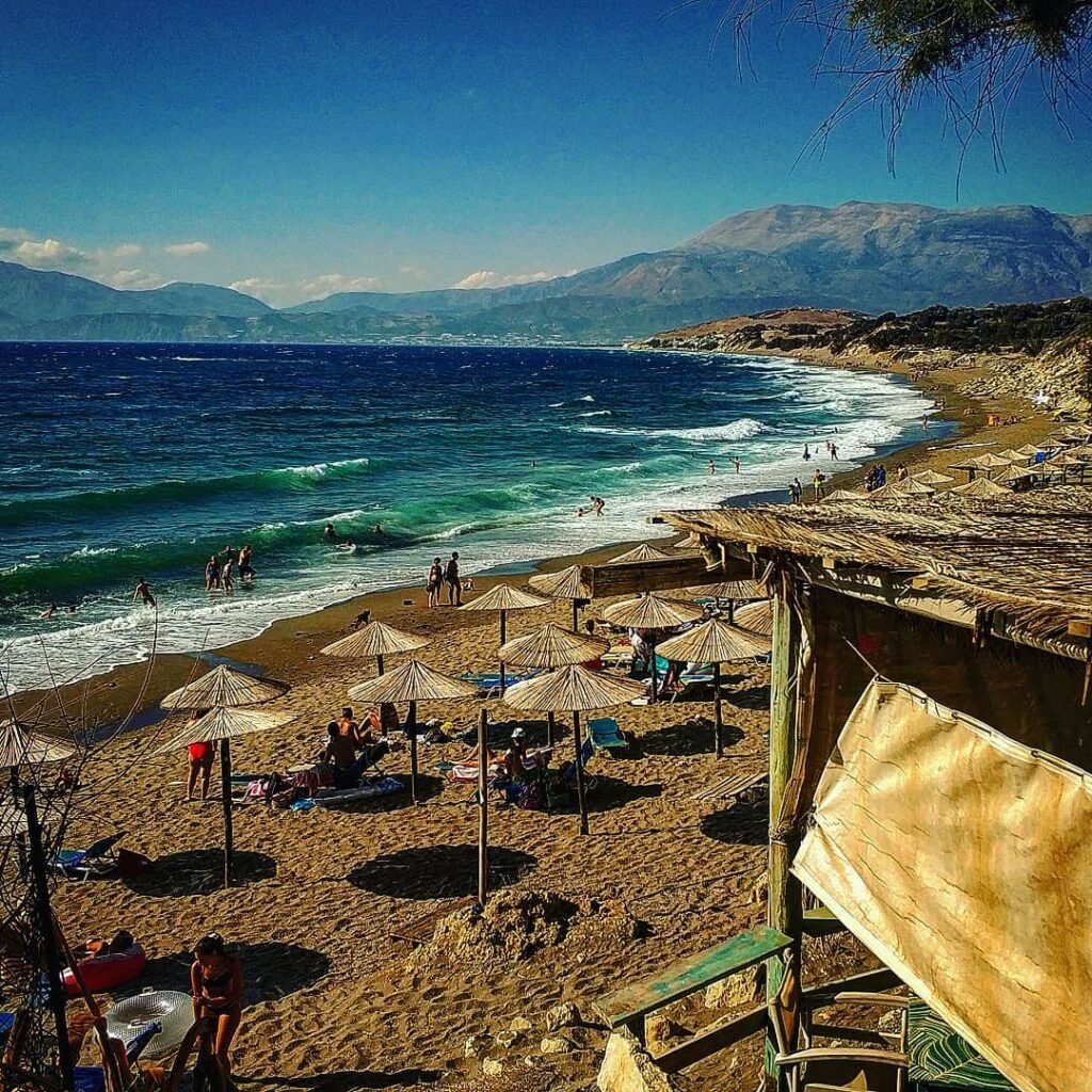 Golden sands and turquoise waves at Komos Beach, nestled in the northern part of Heraklion, Crete, Greece.