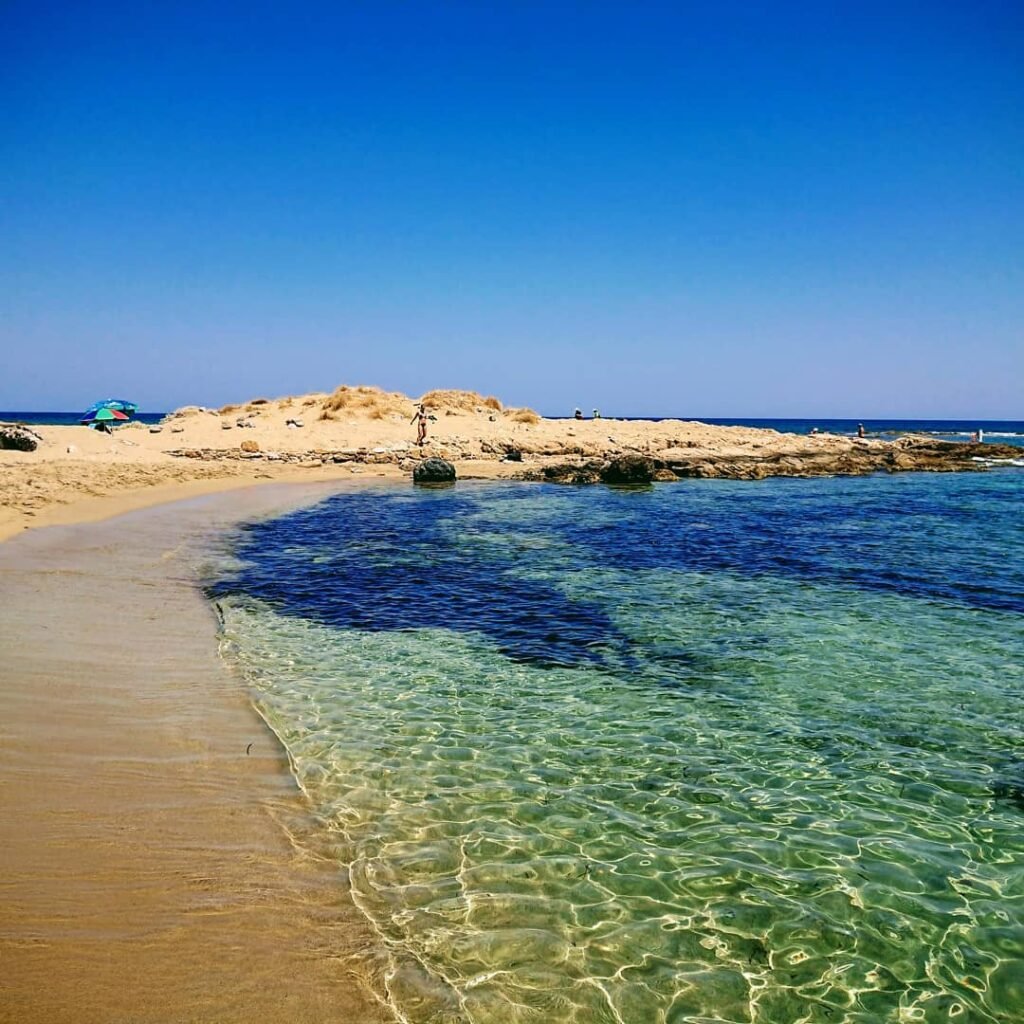 Crystal-clear waters and golden sands at Potamos Beach, Malia, Crete—a serene escape into nature’s beauty.