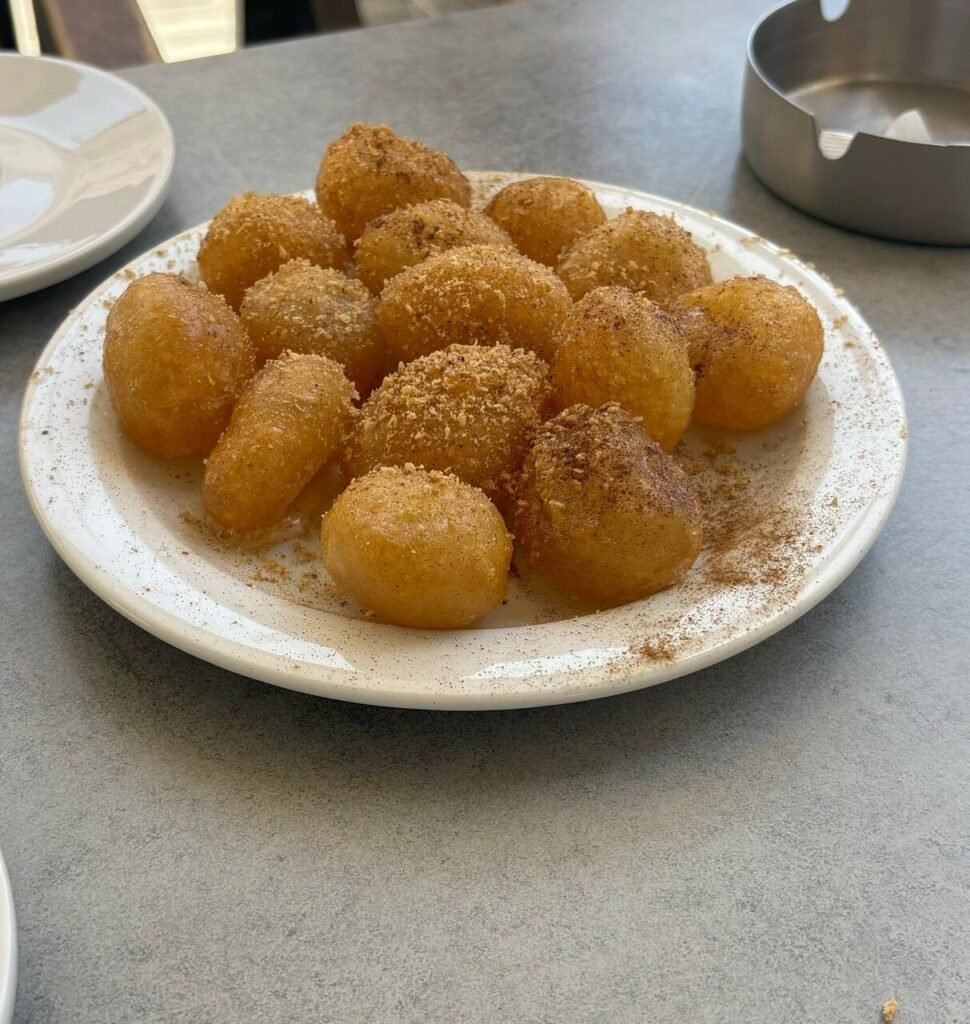 Indulge in crispy, honey-drizzled Greek loukoumades, a sweet highlight of the walking food tour in Chania, Crete.