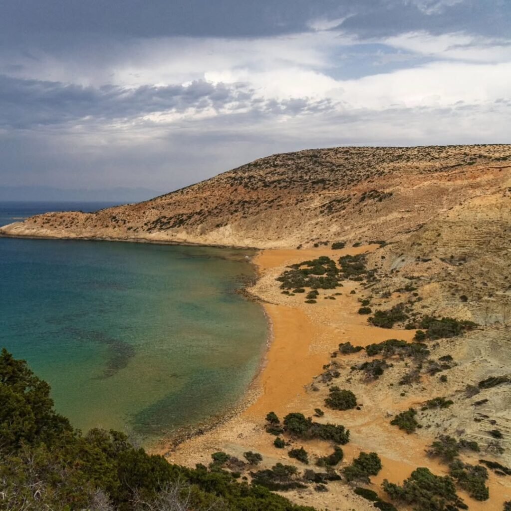 The red sands of Potamos Beach shimmer like fire at sunset, where wild beauty and solitude await those willing to make the journey. 