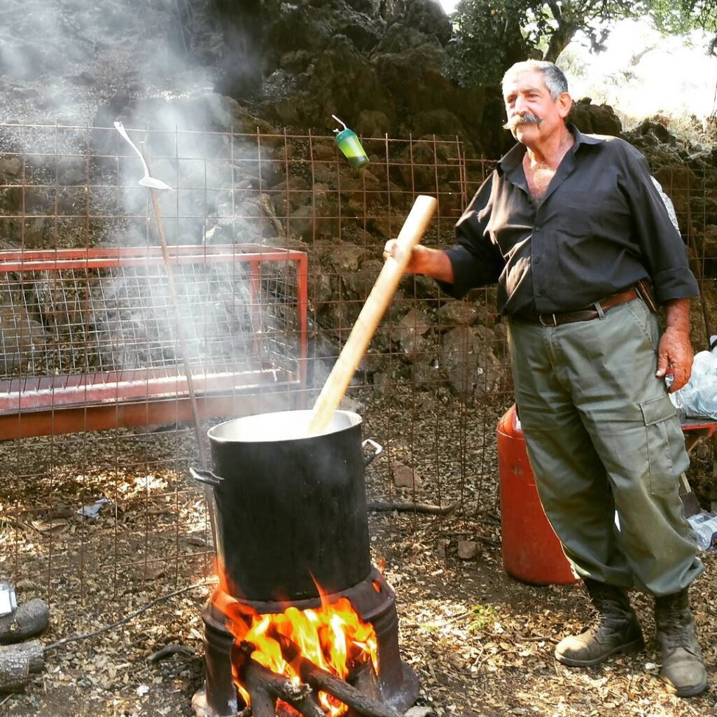 High in the Lefka Ori mountains, a Cretan farmer stirs fresh milk over an open fire – the first step in crafting traditional cheeses like tyrozouli.