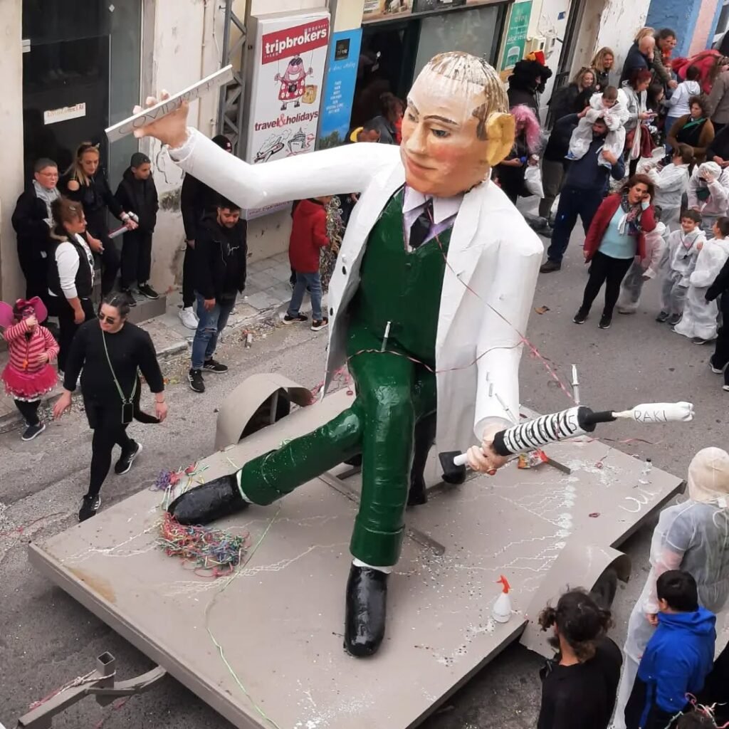 Kalyves Carnival brings the whole village together with handmade floats, costumes, and plenty of laughter—this giant even wields a raki syringe! Local creativity at its best. 