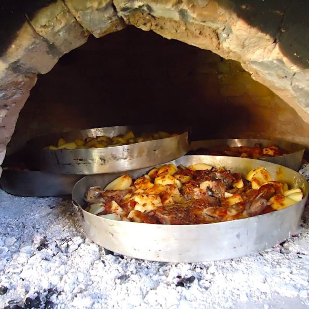 Traditional Easter lamb and potatoes slow-roasting in a wood-fired oven—a beloved Cretan custom that brings families and flavors together during Orthodox Easter celebrations. 