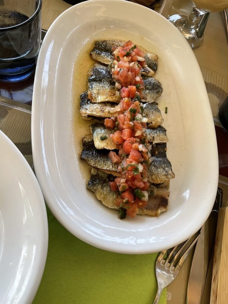 Fresh sardines topped with chopped tomato and herbs at Vai Restaurant Palm Beach — a light and flavourful dish just steps from Crete’s famous palm-lined beach. 
