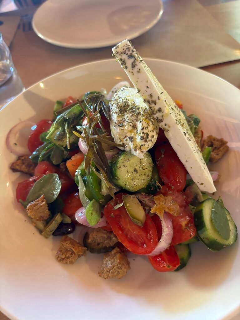 A vibrant Greek salad topped with both Feta and Mizithra cheese—just one of the farm-to-table delights you’ll enjoy surrounded by the peaceful nature of Milia.
