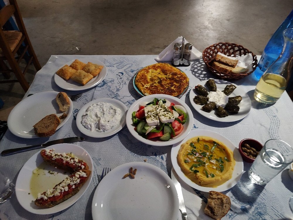 At Taverna Piperia in Pefki, a vibrant spread of Cretan mezze awaits, featuring fresh Greek salad, tzatziki, dolmades, fava, and crispy cheese pies, all paired with local wine. Photo Credit: Piperia.