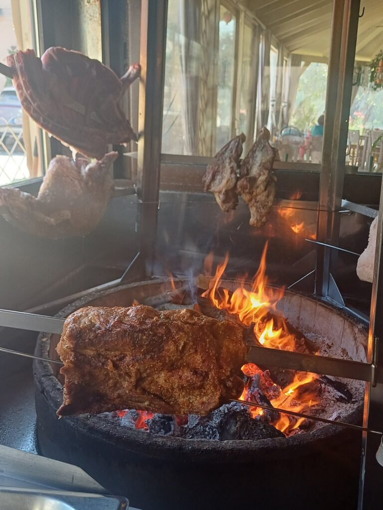Traditional antikristo lamb roasting over an open fire at To Antikristo in Perivolia, one of the best Chania tavernas for meat lovers.