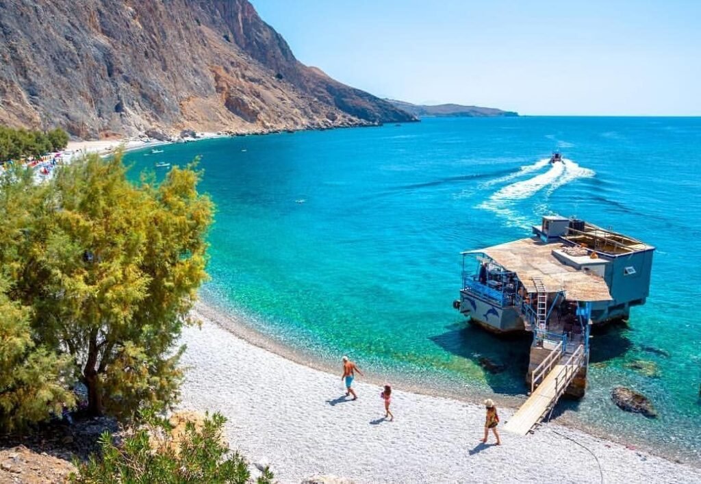 Glyka Nera (Sweet Water Beach) showcases why the hidden beaches in Crete often surpass famous Elafonissi, with freshwater springs bubbling through pebbles beneath towering 500-meter cliffs. This magical spot proves that the most extraordinary beaches in Crete are often the ones that require a little adventure to reach.