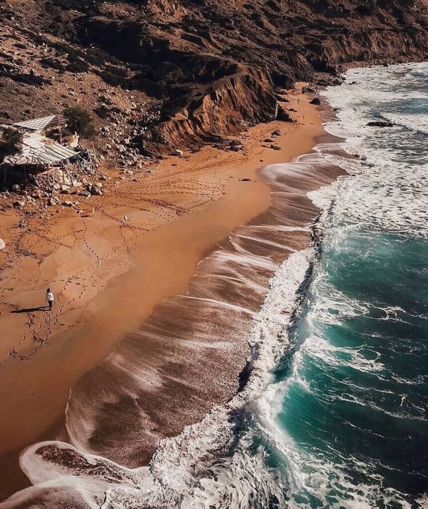 Red Beach's striking crimson sands create an otherworldly landscape that shifts from deep red to ochre throughout the day, capturing the bohemian spirit that made this Crete destination famous among free spirits since the 1960s.