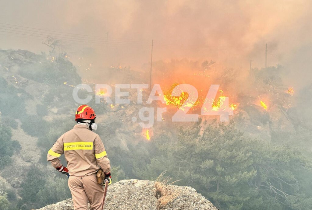 A firefighter surveys the massive fires spreading across southeastern Crete, as flames consume the forested landscape near Ierapetra. The blaze has scorched at least 6 kilometers of terrain. 