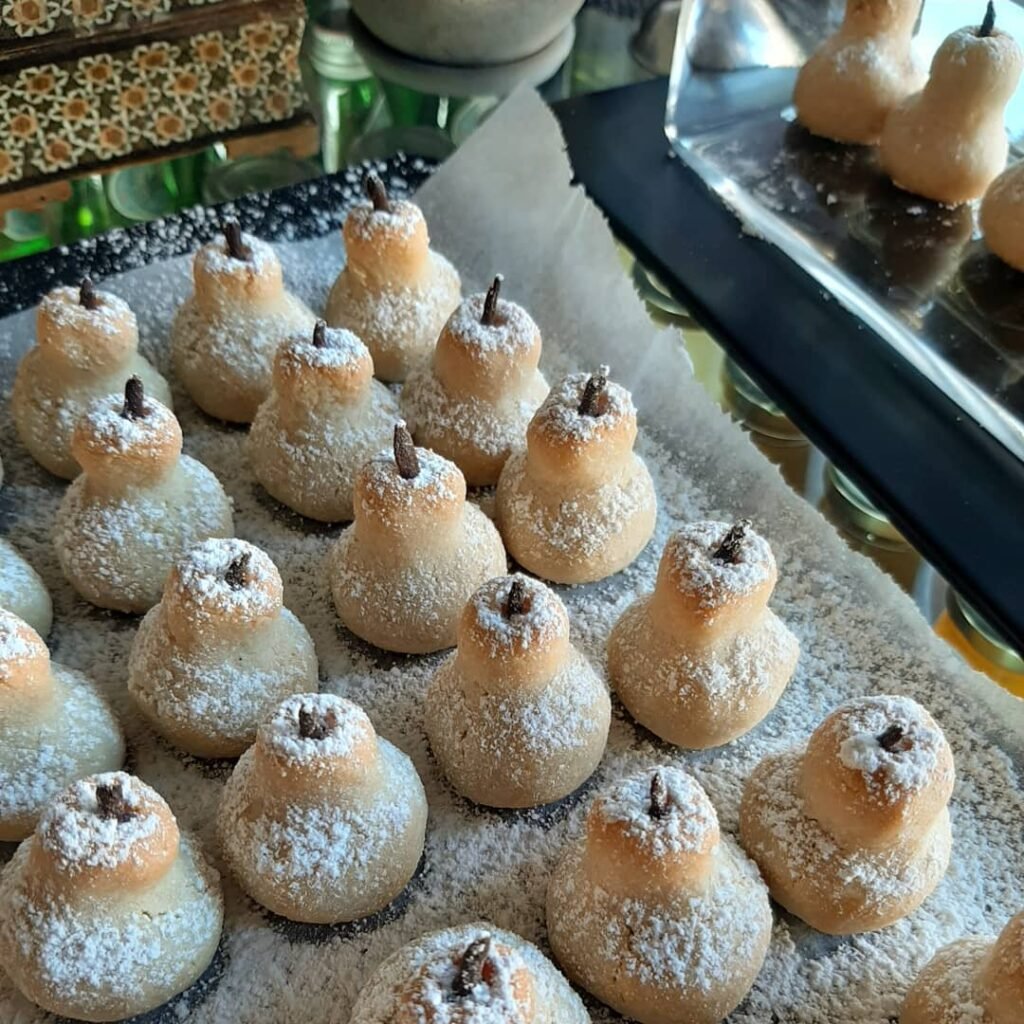 Tender pear-shaped amygdalota cookies showcase the refined elegance of Greek desserts in Crete with their delicate almond flavor and powdered sugar coating. 