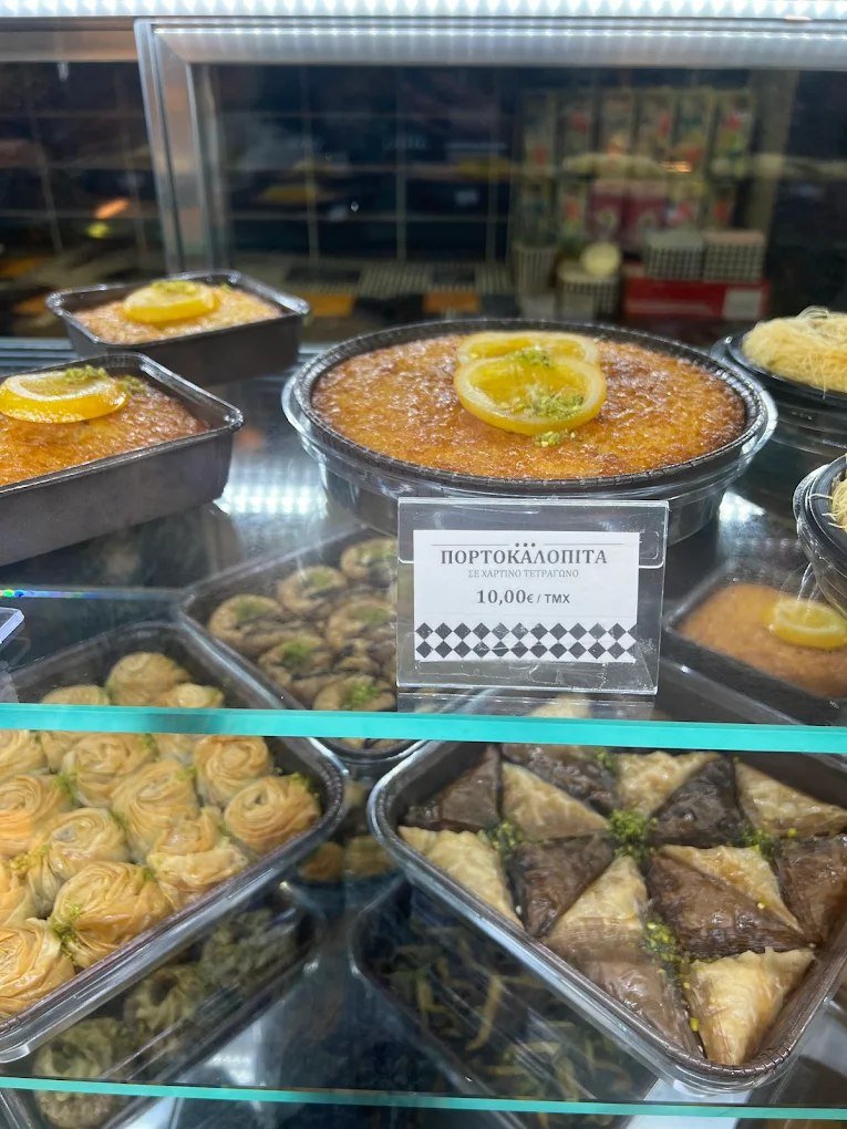 Fresh portokalopita (Greek orange pie) and traditional sweets displayed at Kritikos Fournos in Heraklion, where homemade desserts like this citrus-infused cake showcase the bakery's blend of traditional recipes and modern presentation.