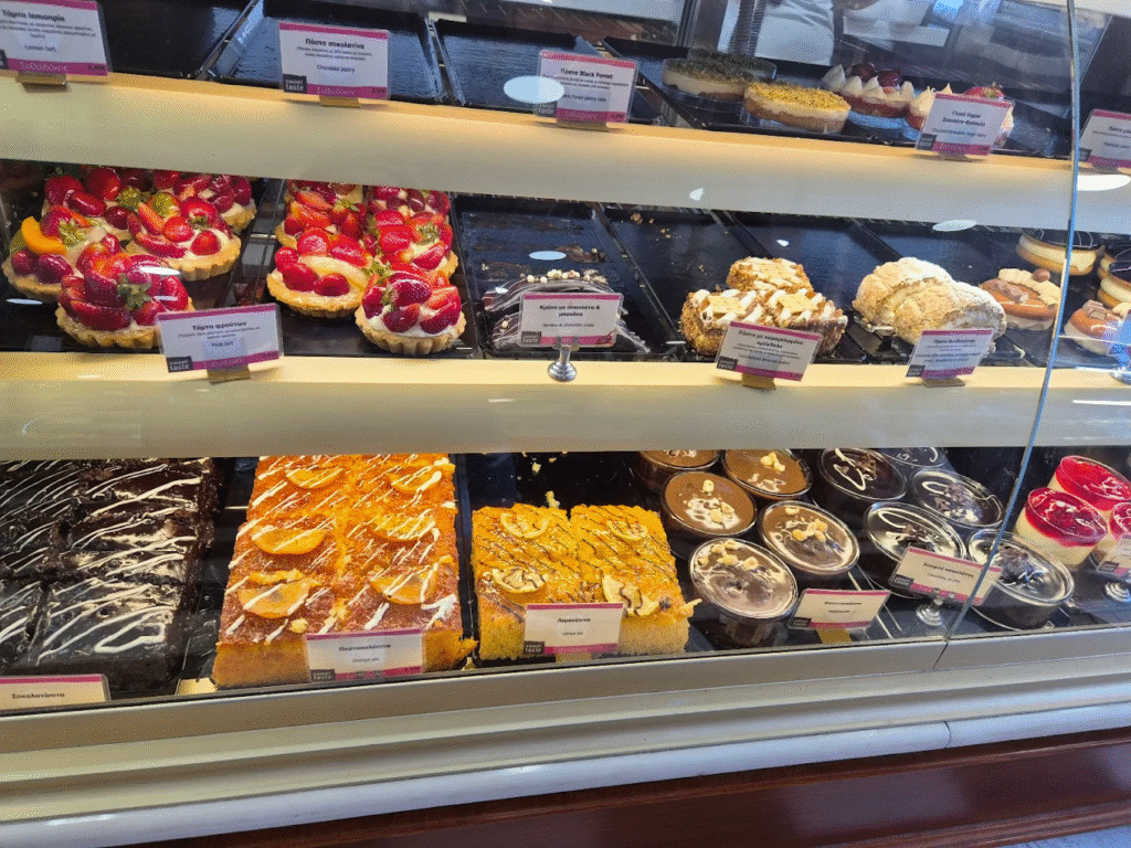 The impressive display case at Savoidakis Bakery in Chersonissos showcasing fresh strawberry tarts, traditional Greek sweets, and modern pastries that represent the variety and quality that has made this family bakery chain one of Crete's most respected brands.