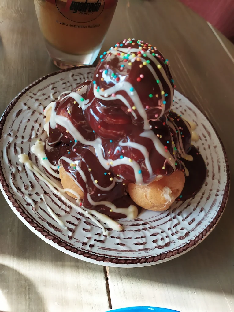 Whimsically decorated dessert at Spells Café Patisserie showcasing the playful presentation that delights both kids and adults, where traditional treats get a magical makeover with colorful sprinkles and creative chocolate drizzles.