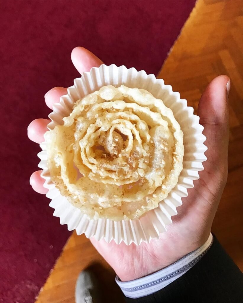 Crispy spiral xerotigana drizzled with golden honey and sprinkled with sesame seeds, capturing the festive spirit of traditional Cretan celebrations. 