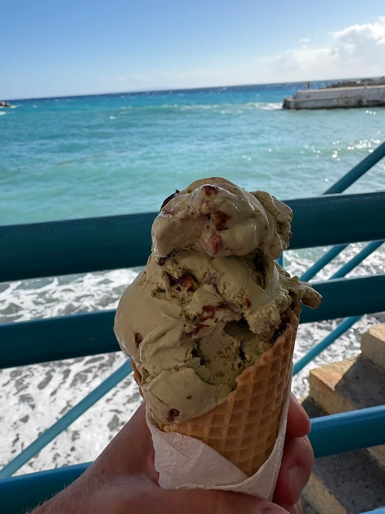 Homemade pistachio ice cream from Cafe Despina enjoyed on the Chora Sfakion seafront, where the turquoise waters of the Libyan Sea create the perfect backdrop for this beloved café's legendary desserts. 