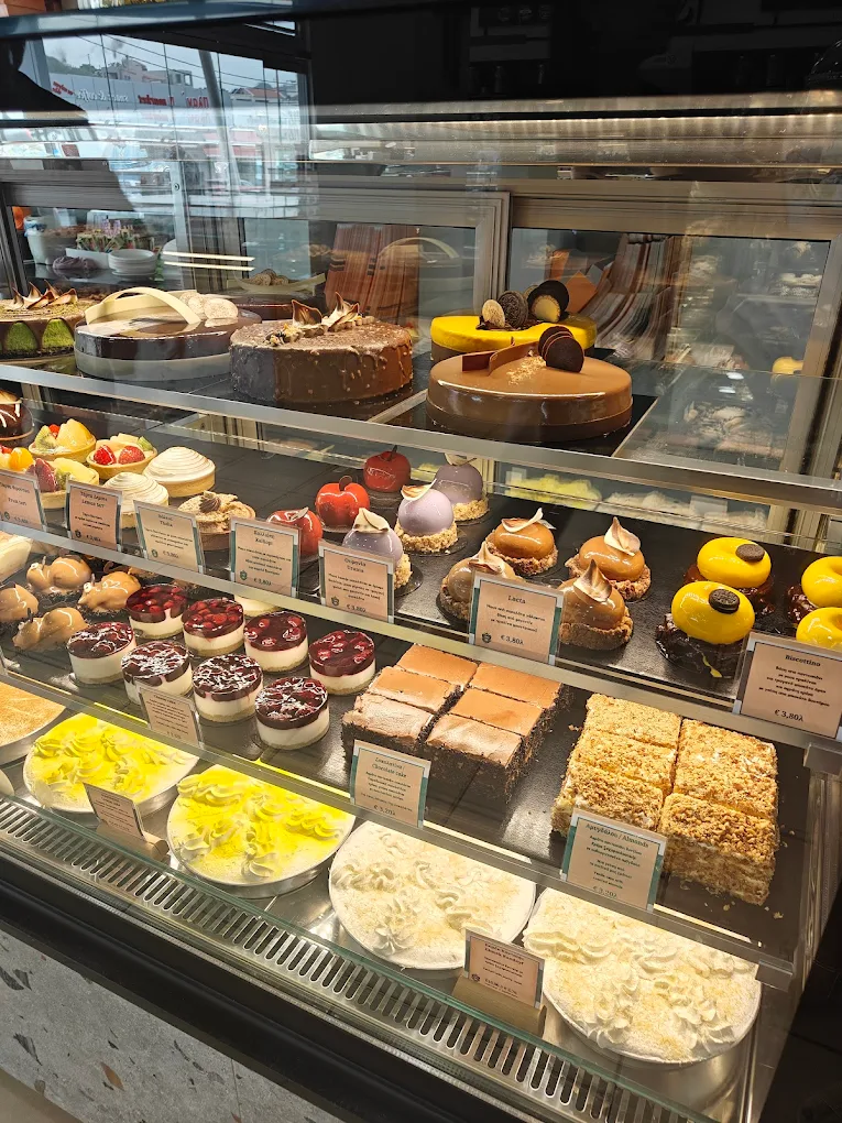 The elegant pastry display at Monterno Café & Patisserie showcasing their famous yo-yos, mousse cakes, individual tarts, tiramisu cups, and celebration cakes that have made this family-run institution a Chania favorite for over 75 years. 
