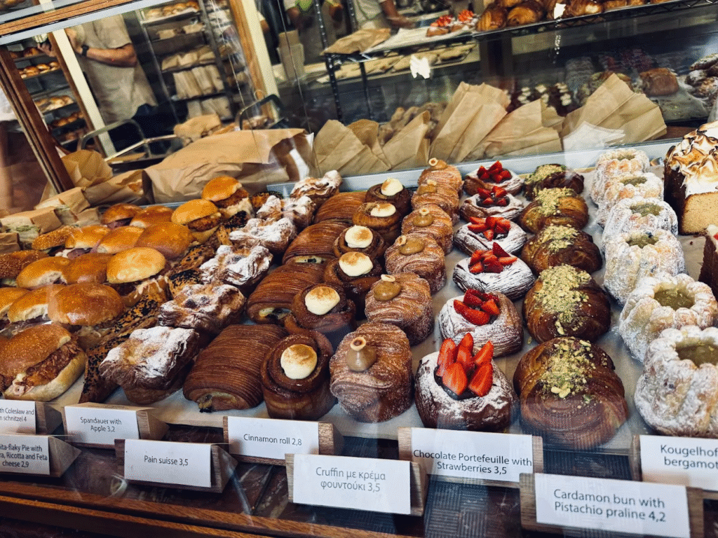 The tempting pastry display at Red Jane Bakery showcasing pistachio-cardamom buns, chocolate portefeuille with strawberries, cinnamon rolls, and pain suisse that draw crowds to this innovative bakery in Chania, Crete. 