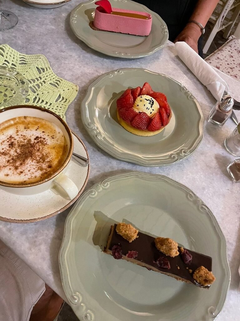 Artfully plated desserts at Sketi Glyka including a fresh strawberry tart, chocolate dessert, and a vibrant pink mousse cake, showcasing the patisserie's mastery of both traditional and modern pastry techniques.